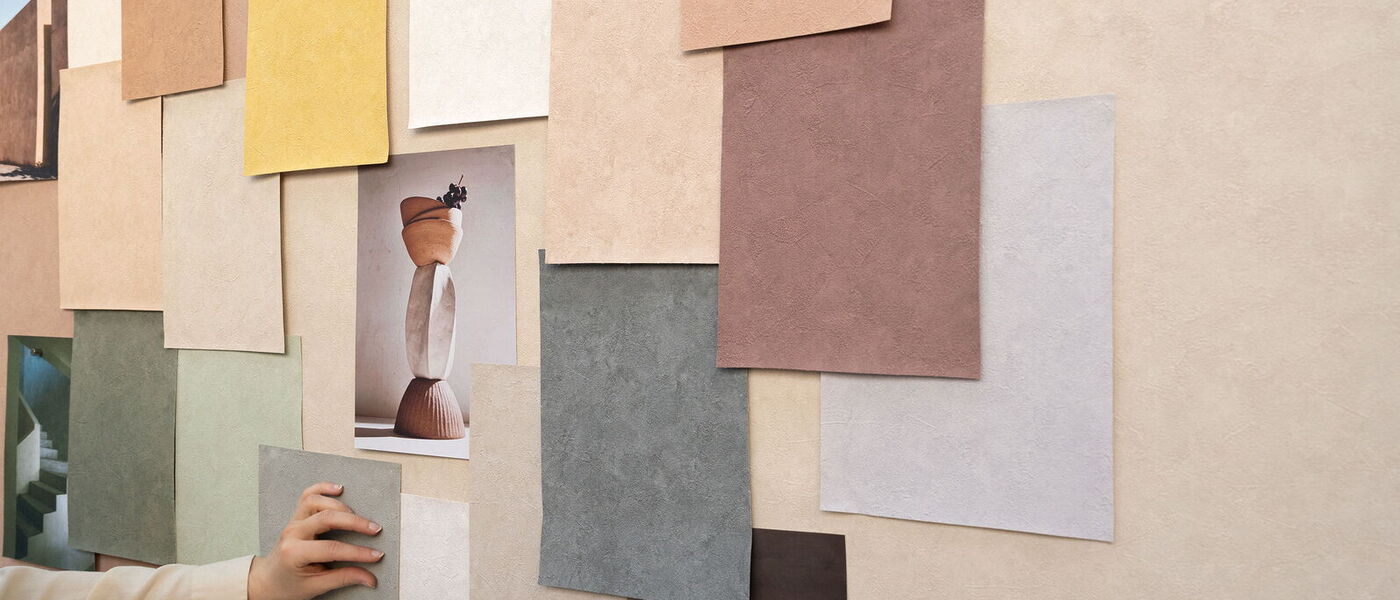 Kreative Materialstudie und Farbinspiration für die nachhaltige Vescom Vinyl-Wandbekleidung Clay mit verschiedenen Farbmustern an einer Wand.