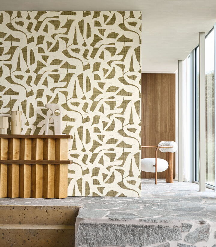 Hochwertige Design-Tapete Cana Kaki von Casamance mit einem modernen, abstrakten Grafikmuster in Natur- und Olivtönen, inszeniert in einem minimalistischen Raum.